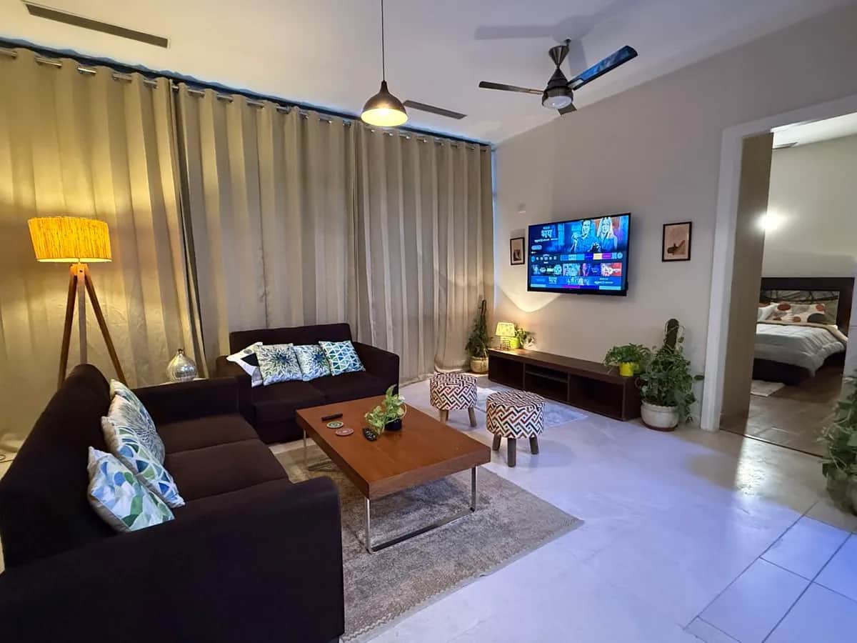 IREOグランドアーチ 3BHK 広々としたリビングルーム — ダークLソファとペンダントライト（グルガオン）