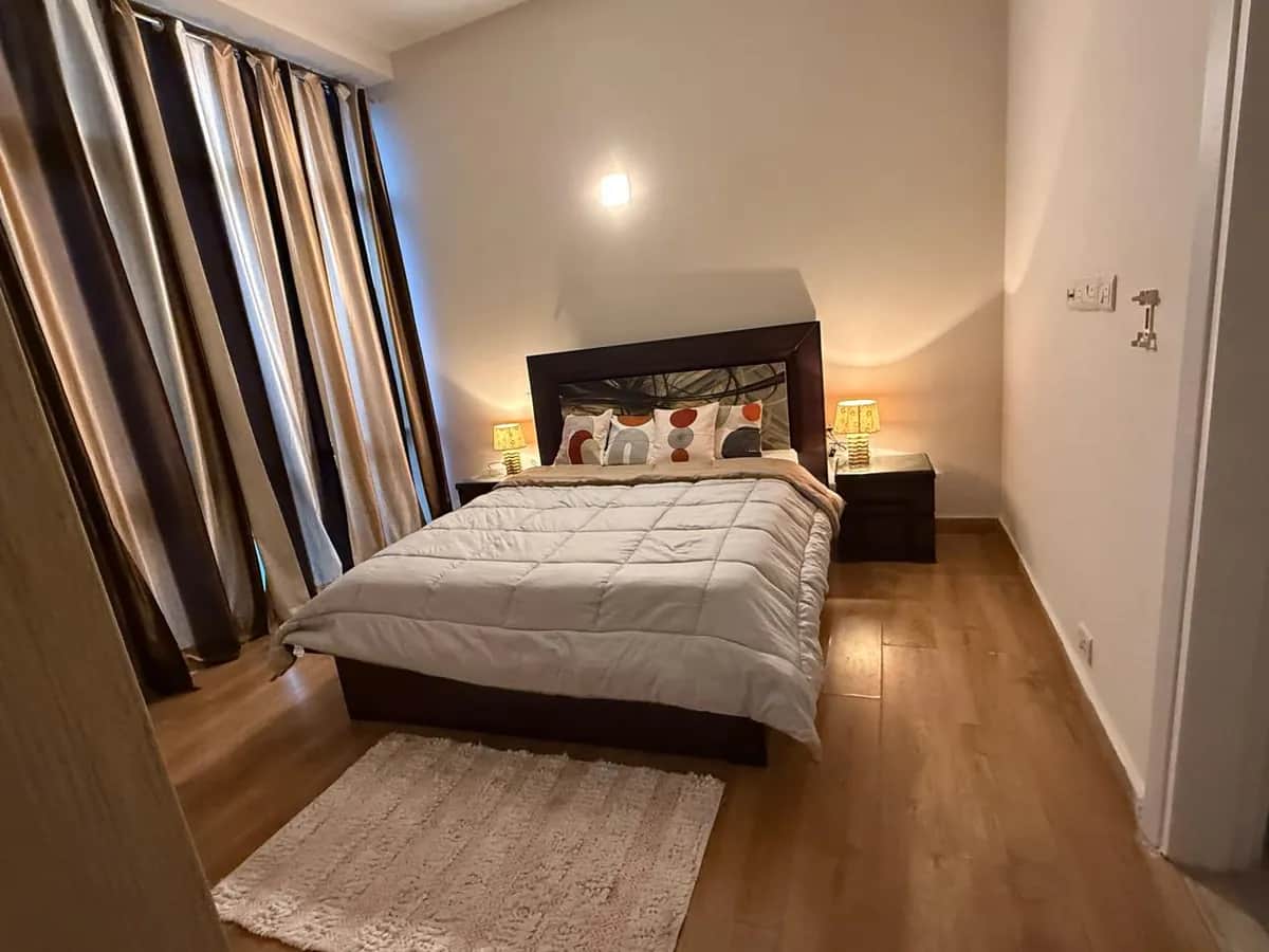 IREOグランドアーチ 3BHK 第3寝室 — ダブルベッドと温かみのある照明（グルガオン セクター58）